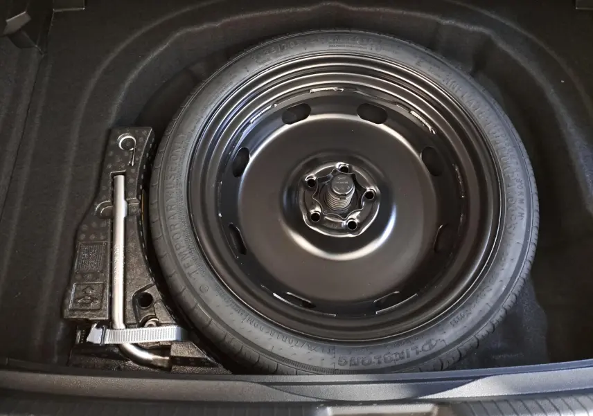 Roue de secours et cric dans le coffre d'une Volkswagen Golf 1.5 eTSI 116 DSG7 Bleu Glacier, vue de dessus.