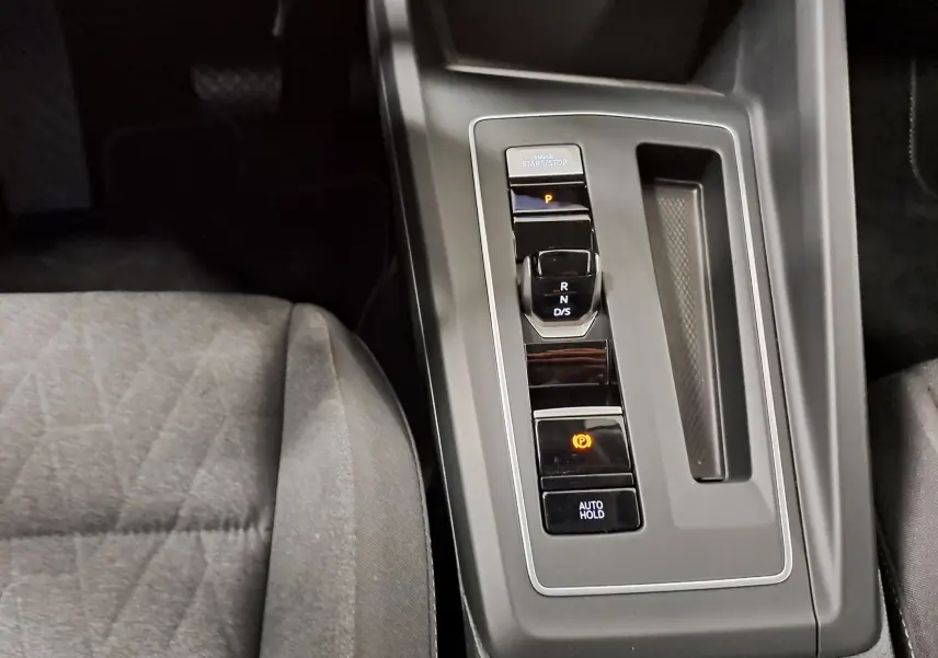 Vue rapprochée de la console centrale de la Volkswagen Golf 1.5 eTSI 116 DSG7, avec levier de vitesses automatique et siège tissu gris.