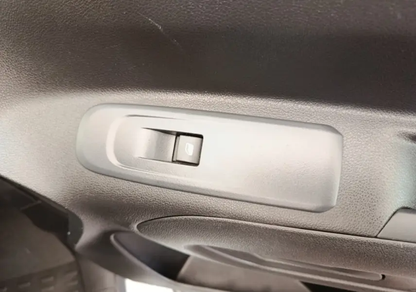 Gros plan sur l'interrupteur de lève-vitre côté conducteur dans l'habitacle du Peugeot Partner blanc.