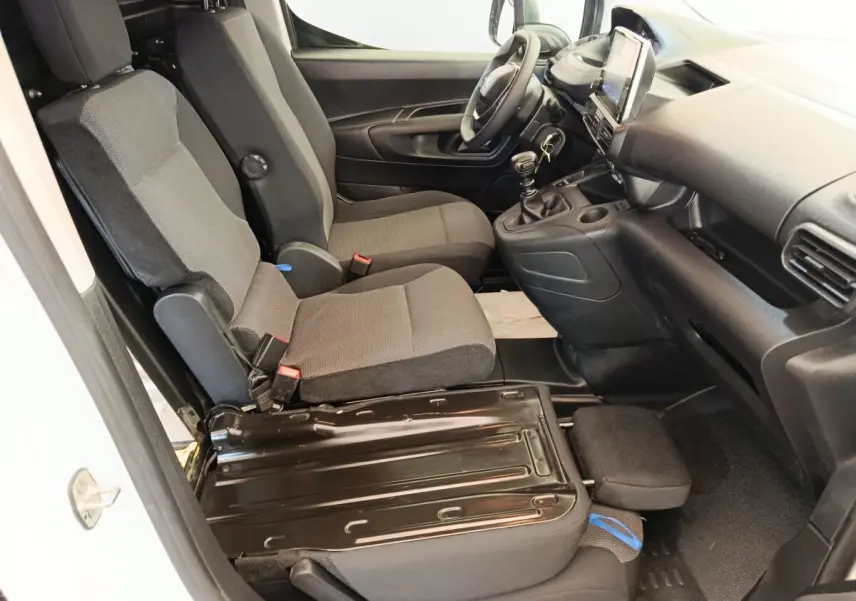Vue intérieure côté conducteur du Peugeot Partner blanc 2022, montrant les sièges avant et la console centrale avec boîte manuelle.