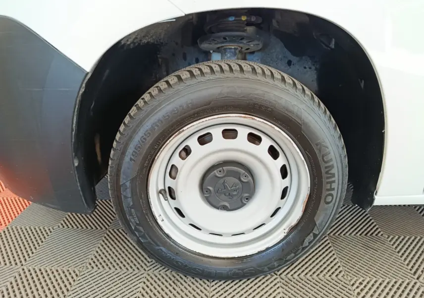 Gros plan sur la roue avant gauche blanche d’un Peugeot Partner blanc, avec jante acier et pneu Kumho visible.