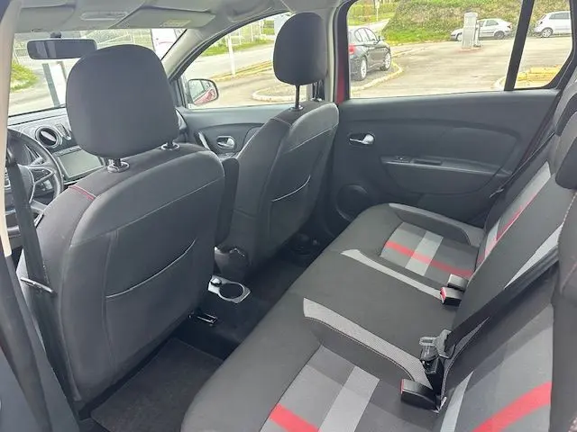 Vue intérieure arrière de la Dacia Logan MCV rouge 2019, montrant les sièges arrière en tissu gris avec bandes rouges et noires.