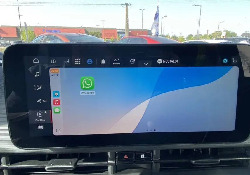 Écran tactile central de la Fiat 500 électrique 2022 affichant Apple CarPlay avec l'application WhatsApp ouverte.
