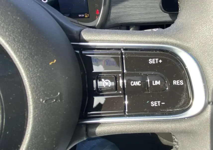 Gros plan sur les commandes du régulateur de vitesse au volant noir de la Fiat 500 électrique 2022.