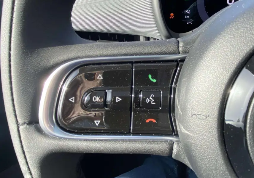 Gros plan sur les commandes au volant noir de la Fiat 500 électrique 2022 avec tableau de bord numérique visible.