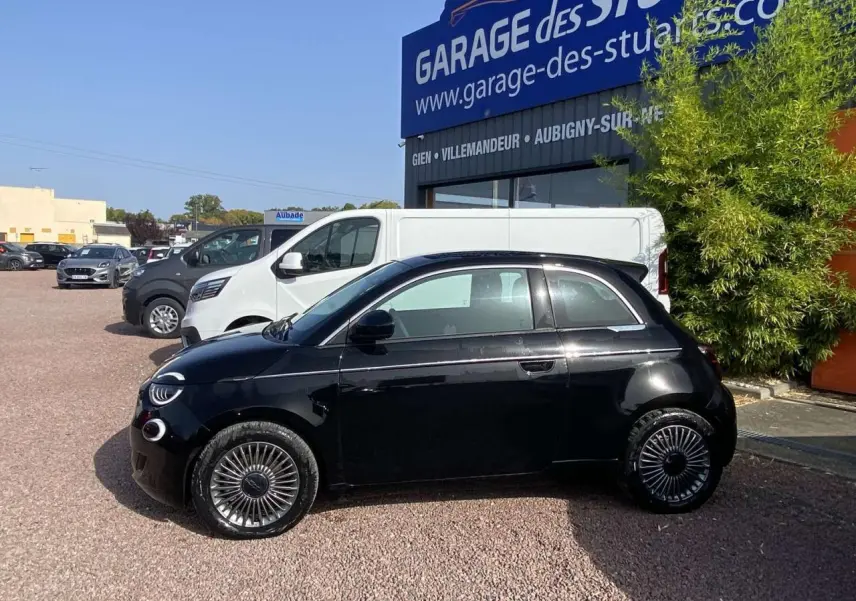 Profil côté gauche de la Fiat 500 électrique noire métal 2022 avec jantes stylisées et baguettes chromées visibles.