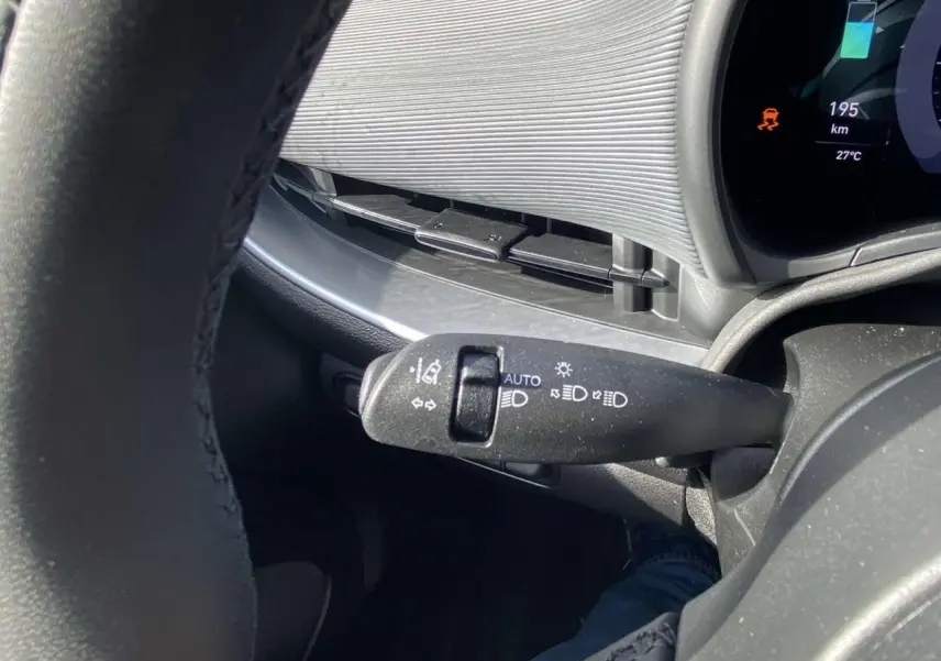Gros plan sur la commande des feux au volant d'une Fiat 500 électrique 2022, planche de bord Technowood visible.