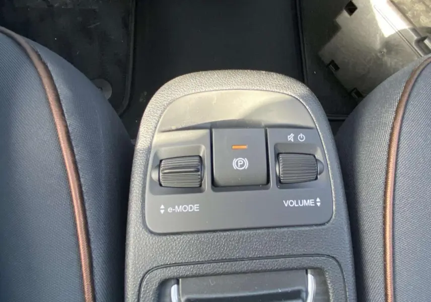 Gros plan sur la console centrale entre les sièges avant en tissu noir avec surpiqûres marron de la Fiat 500 Electrique noire.