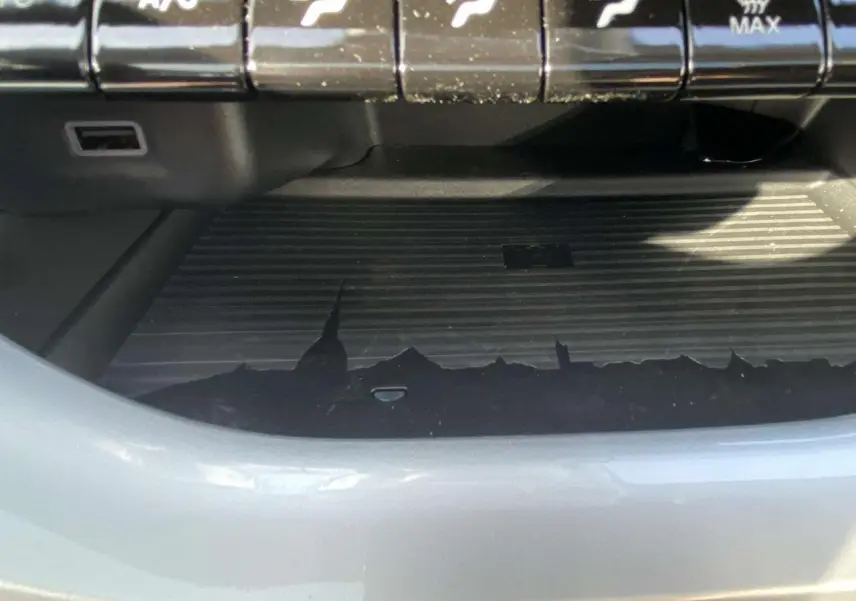 Gros plan sur la console centrale noire avec commandes climatisation et surface de recharge sans fil dans une Fiat 500 Electrique noire.