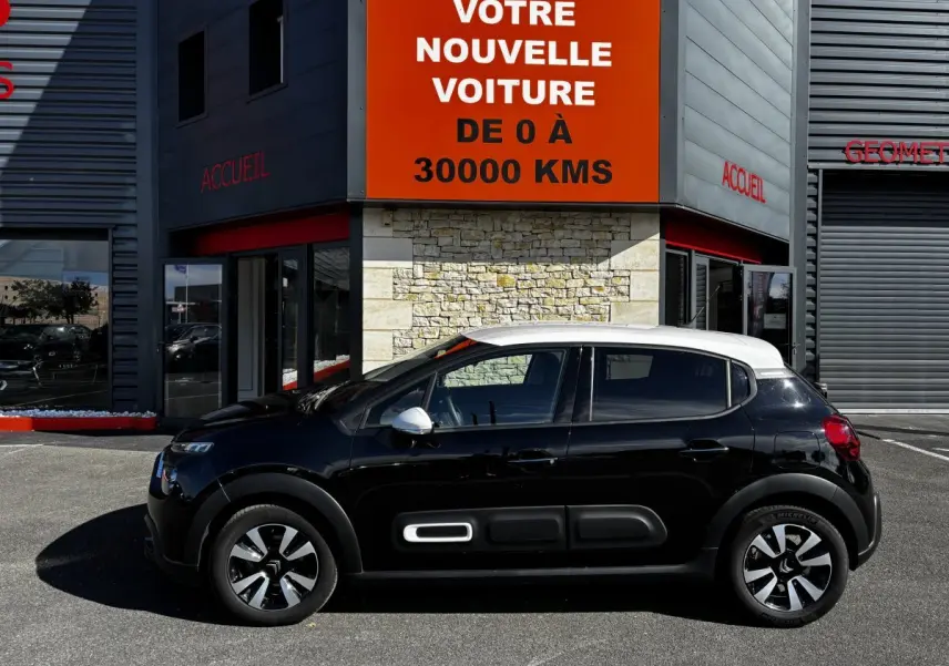 Profil côté gauche d'une Citroën C3 2024 bicolore noir et toit blanc, avec protections latérales caractéristiques.