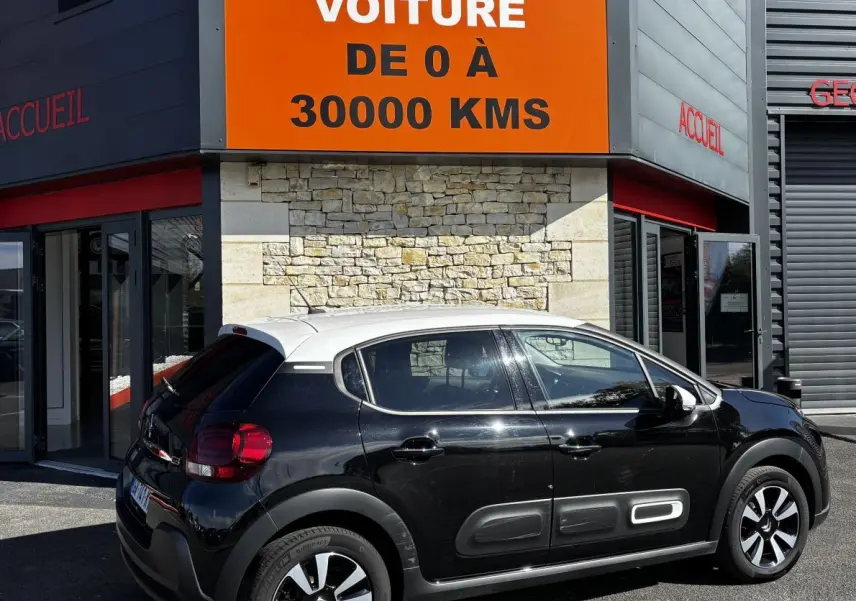 Vue côté gauche arrière d'une Citroën C3 bicolore noir et toit blanc avec protections latérales caractéristiques.