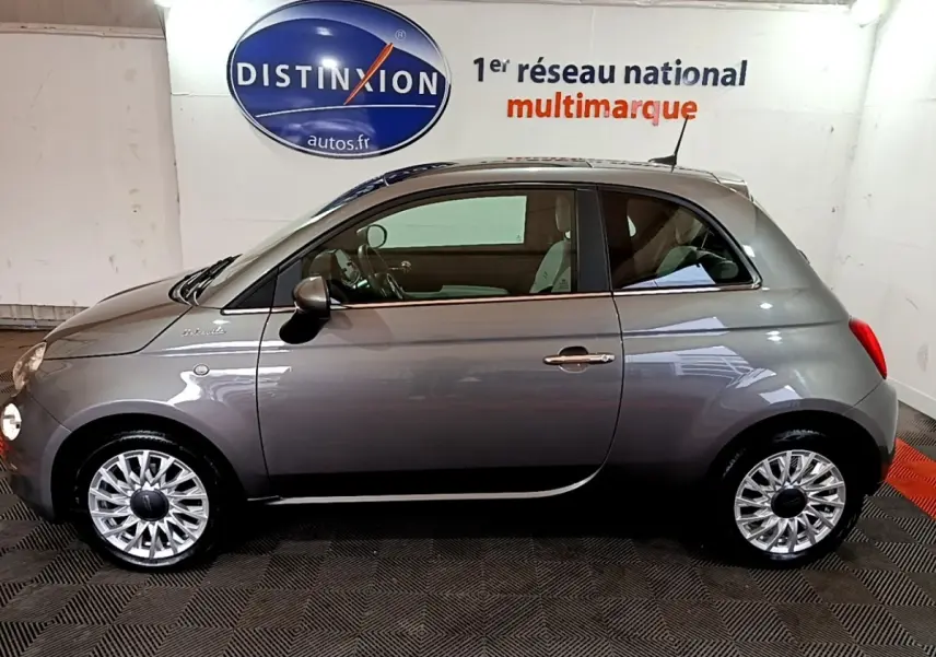 Profil latéral droit d'une FIAT 500 Dolcevita hybride gris foncé avec jantes alliage et intérieur visible.