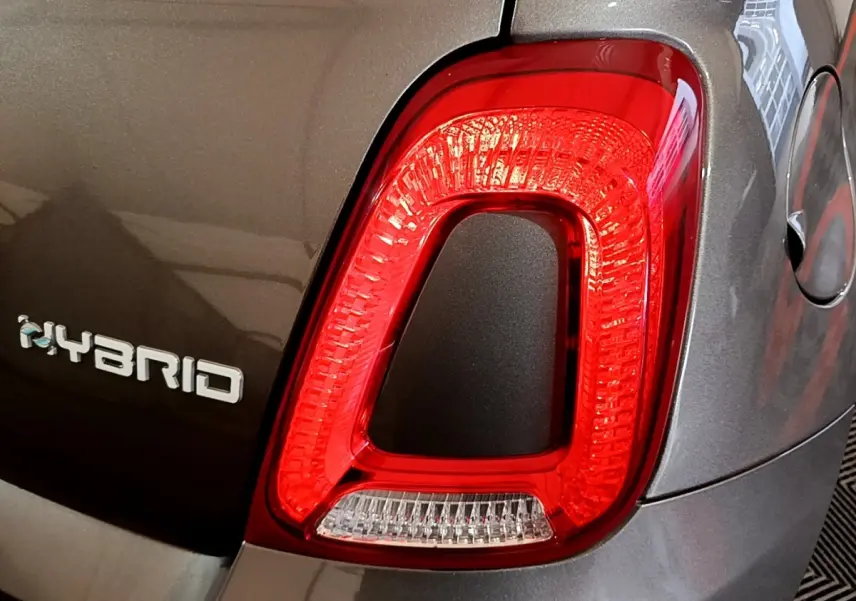 Gros plan sur le feu arrière droit rouge et le logo Hybrid d'une FIAT 500 gris foncé vue de l'arrière.