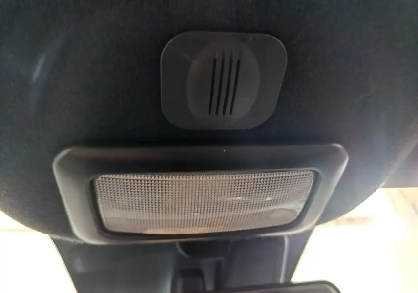 Gros plan sur l'éclairage intérieur et le micro du plafond d'une FIAT 500 gris foncé, vue vers l'avant.