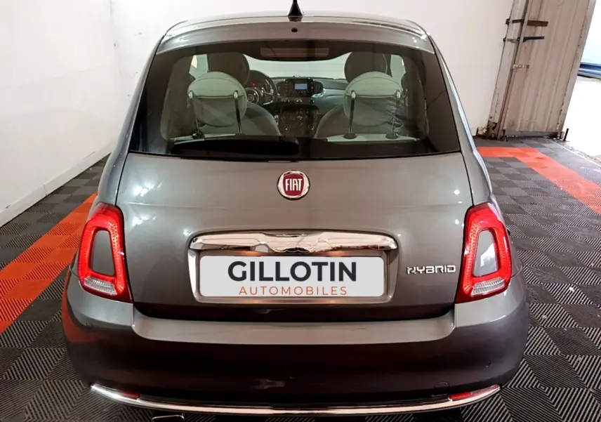 Vue arrière d'une FIAT 500 Hybrid gris foncé, avec feux LED et logo distinctif sur un sol à damiers noir et rouge.