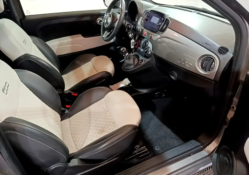 Vue intérieure côté conducteur de la Fiat 500 Hybrid 2021 avec sièges bi-ton beige et noir et tableau de bord gris.