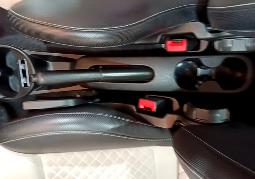 Vue plongeante sur la console centrale de la Fiat 500 Dolcevita, montrant frein à main et sièges en cuir noir.