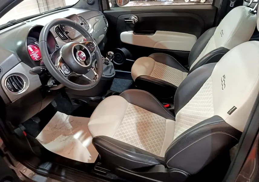 Vue intérieure côté conducteur de la Fiat 500 Hybrid 2021, sièges bicolores cuir noir et beige avec volant multifonctions.