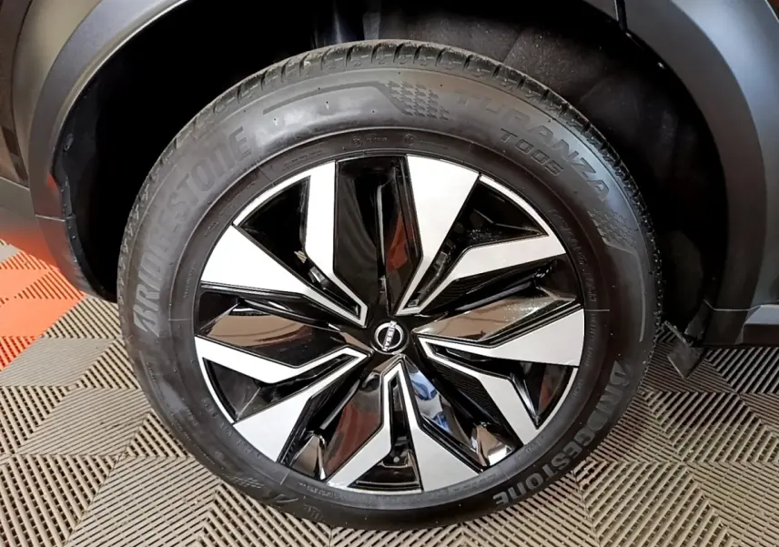 Gros plan sur la roue avant droite noire avec jante alliage bicolore du Nissan Juke 2023 DIG-T 114 BVM6 Acenta.