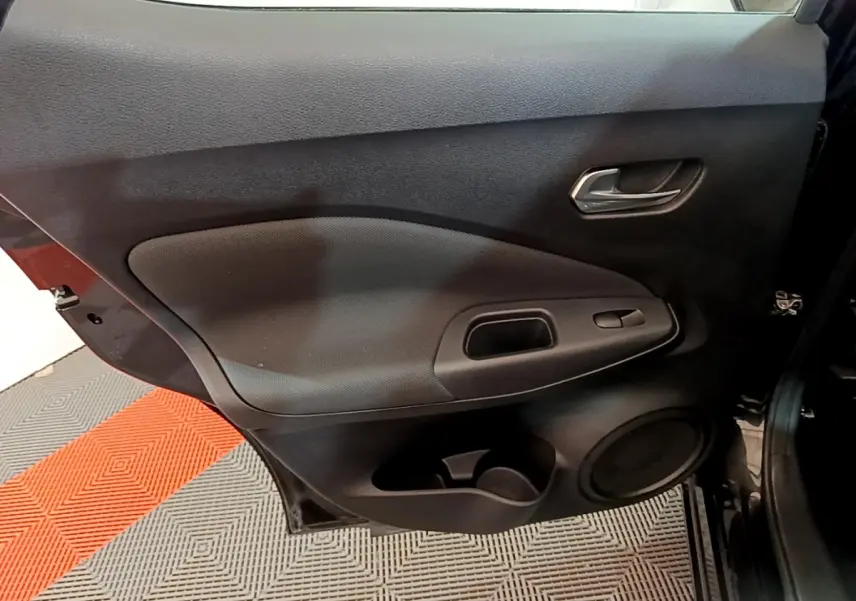 Vue intérieure côté gauche de la porte arrière noire du Nissan Juke 2023 avec poignée et commande de fenêtre intégrée.