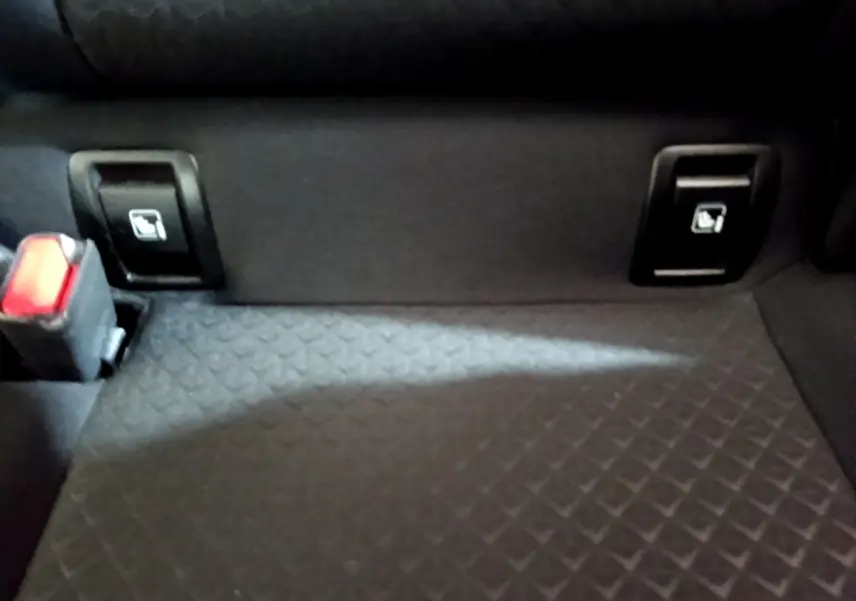 Détail de la banquette arrière noire du Nissan Juke 2023 avec commandes rabattables et ceinture de sécurité.