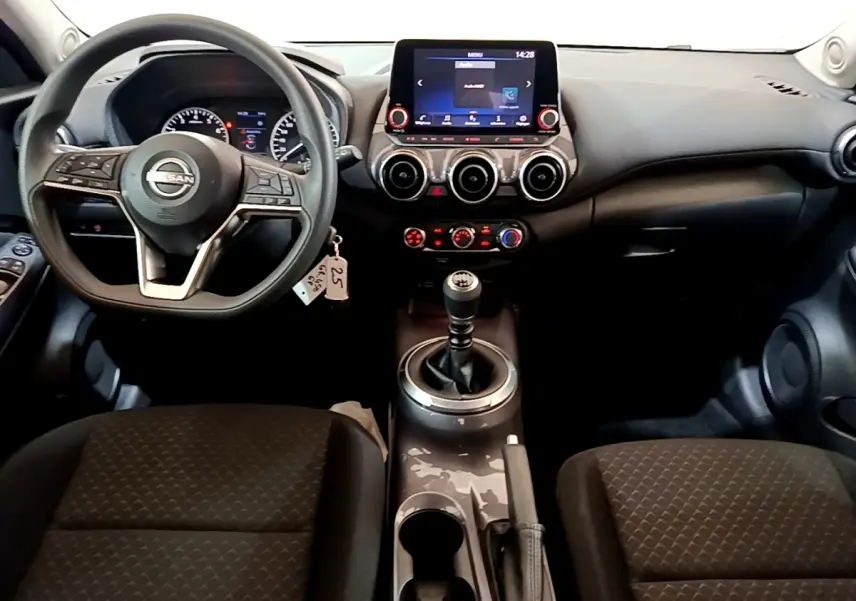 Vue intérieure frontale du tableau de bord noir du Nissan Juke 2023 avec volant multifonctions et écran tactile central.