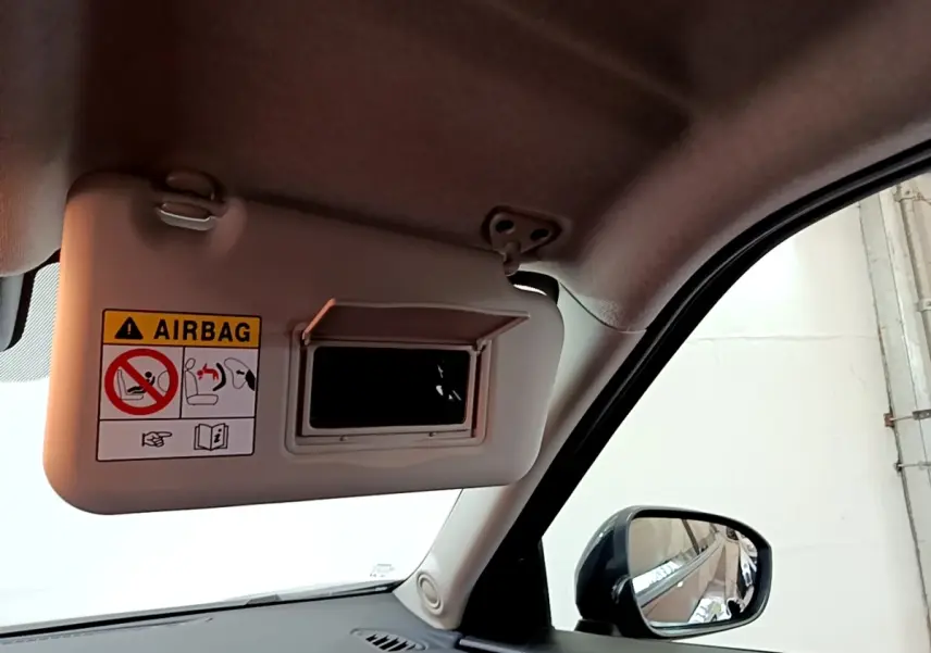 Détail du pare-soleil côté conducteur avec miroir intégré et avertissement airbag dans un Nissan Juke noir 2023.