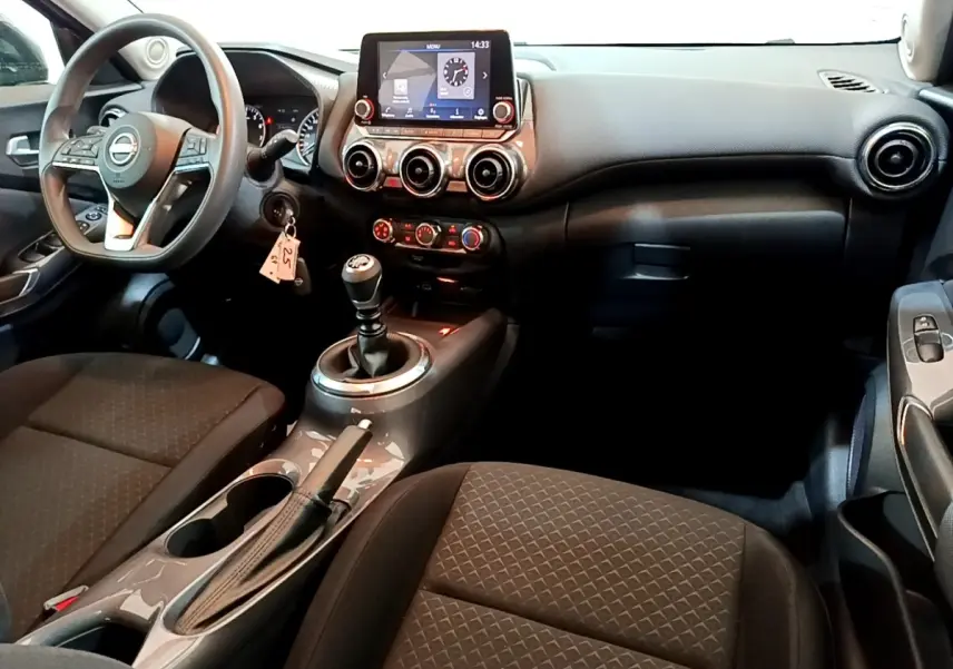 Intérieur noir du Nissan Juke 2023 vu côté conducteur, avec tableau de bord digital et boîte manuelle.
