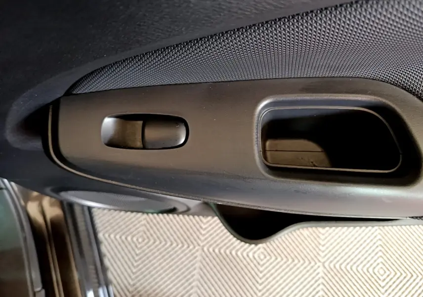 Gros plan sur la poignée intérieure de porte côté conducteur du Nissan Juke noir 2023, avec bouton de verrouillage.