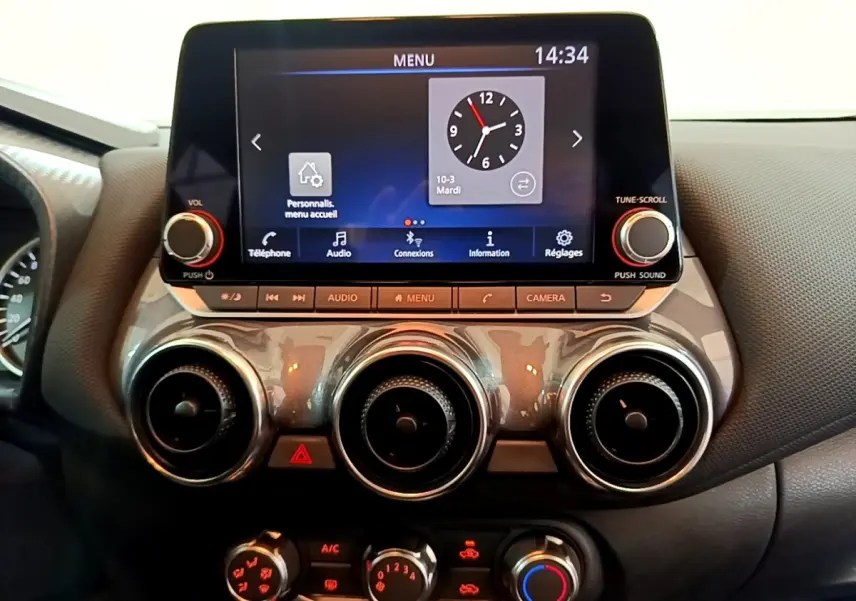Vue rapprochée du tableau de bord noir du Nissan Juke 2023 avec écran tactile et commandes circulaires d’aération.
