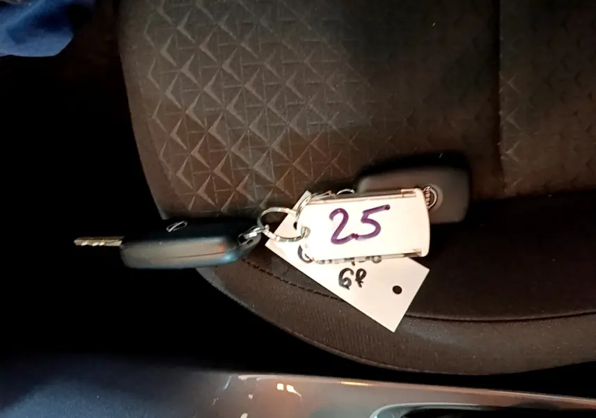 Clé de voiture Nissan posée sur un siège tissu noir à motifs géométriques, vue rapprochée intérieure.