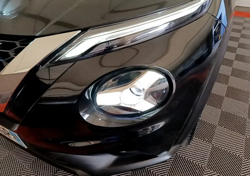 Gros plan sur le phare avant droit du Nissan Juke noir 2023, mettant en valeur ses feux LED et la calandre.