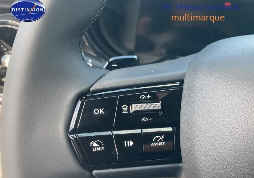 Gros plan sur les commandes au volant à gauche de l'Alfa Romeo Junior 1.2 hybride grise, montrant les boutons d'assistance et de régulation.