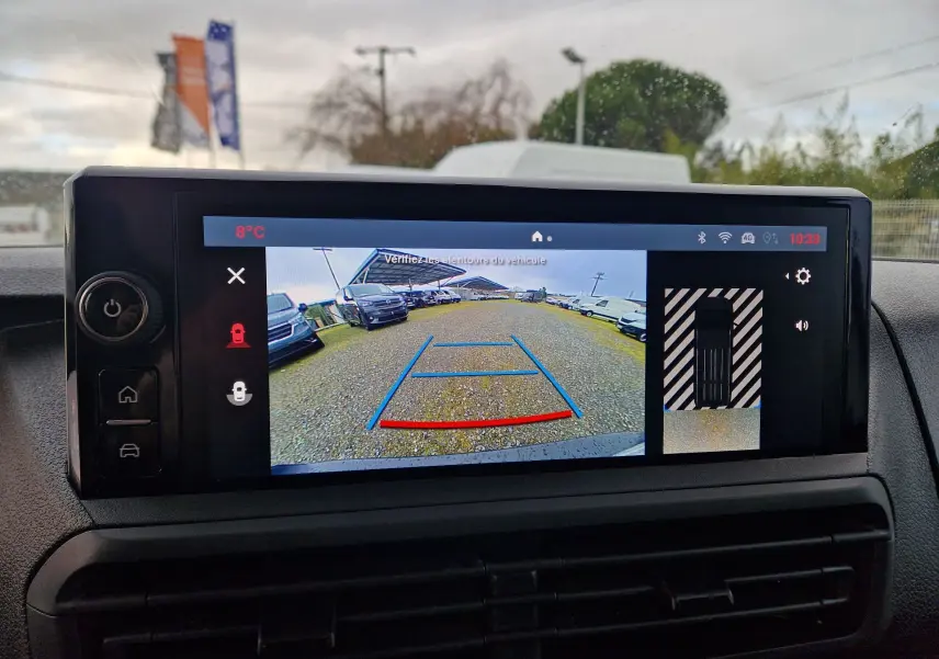 Écran intérieur montrant la caméra de recul avec vue arrière large sur un parking, dans un FIAT Scudo Fourgon blanc 2024.