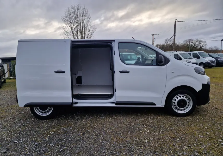 Vue de profil côté droit d’un FIAT Scudo Fourgon blanc 2024 avec porte latérale coulissante ouverte montrant l’espace de chargement vide.