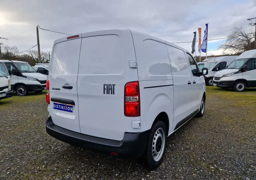 Vue 3/4 arrière droite d’un FIAT Scudo Fourgon blanc 2024 avec plaques arrière et feux rouges visibles sur un terrain extérieur.