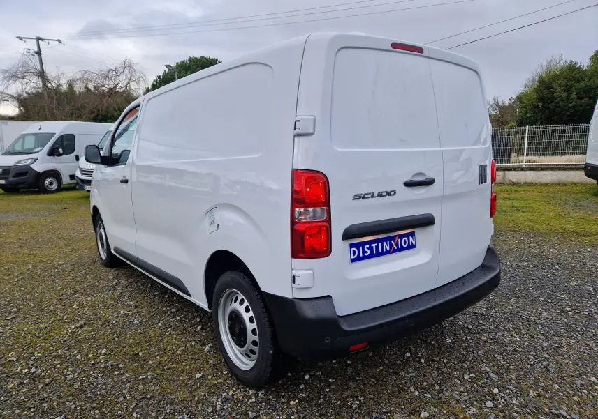 Vue 3/4 arrière droite d’un FIAT Scudo Fourgon blanc 2024 avec plaque de protection et feux rouges visibles.