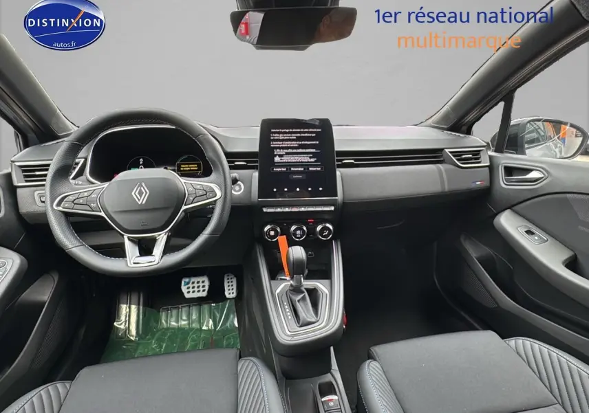 Vue intérieure avant de la Renault Clio V gris rafale, volant multifonction, écran tactile vertical et levier de boîte auto.