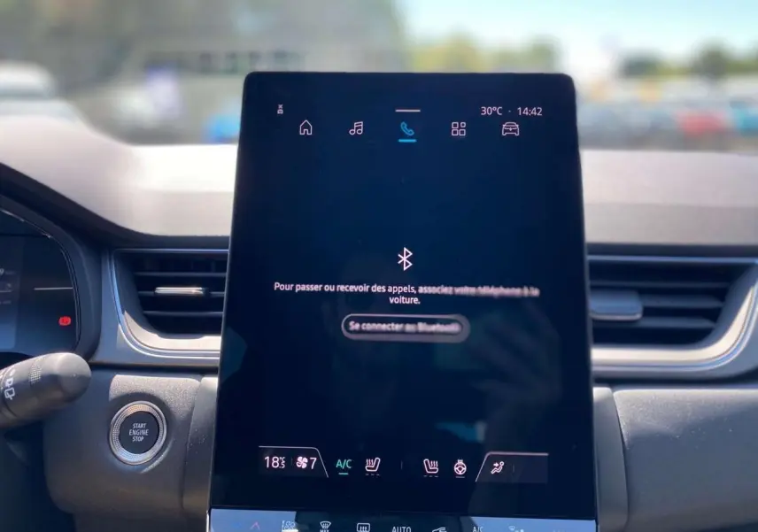Écran tactile central du tableau de bord du Renault Captur 2025, affichant la connexion Bluetooth et commandes climatisation.