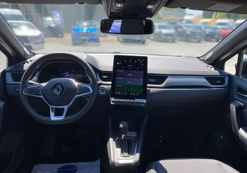 Vue intérieure avant du Renault Captur 2025, tableau de bord moderne avec écran tactile vertical et volant multifonction noir.