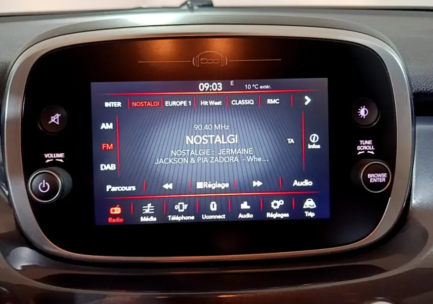 Écran tactile central du tableau de bord de la Fiat 500X gris foncé, affichant la radio sur la station Nostalgie.