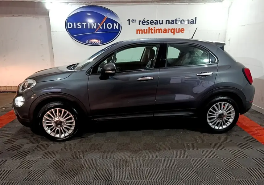 Vue de profil côté gauche d'une FIAT 500X gris foncé 2019 avec jantes alliage et rétroviseurs électriques dans un showroom.