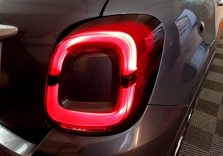 Gros plan sur le feu arrière droit rouge d’un FIAT 500X gris foncé, avec la trappe à carburant visible à côté.