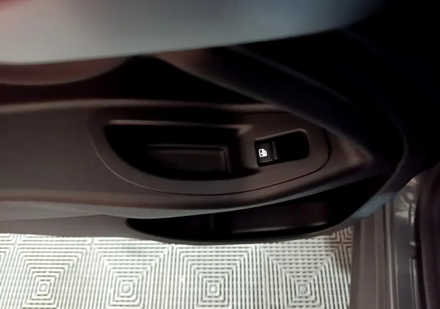 Gros plan sur la commande de verrouillage des portes côté conducteur du FIAT 500X gris foncé, intérieur sombre.