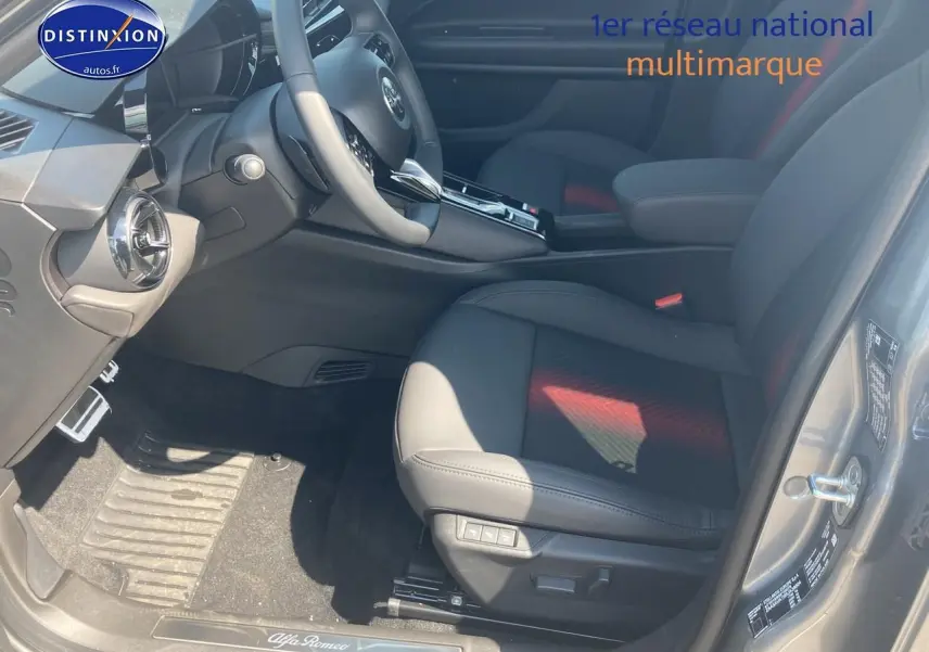 Vue intérieure côté conducteur de l'Alfa Romeo Junior 1.2 hybride gris t/noir, sièges en cuir noir avec surpiqûres rouges.