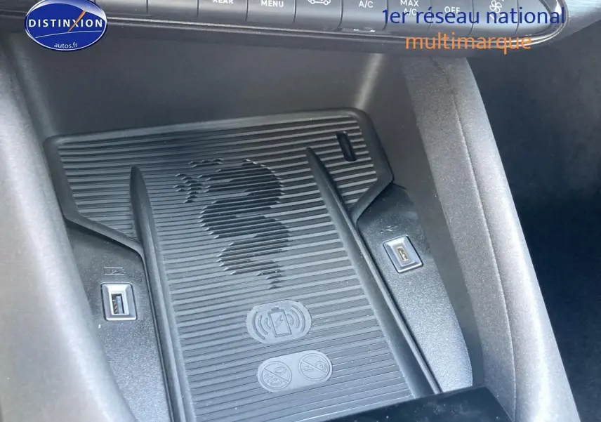 Détail du chargeur à induction avec logo serpent Alfa Romeo, entouré de ports USB dans l'habitacle noir.