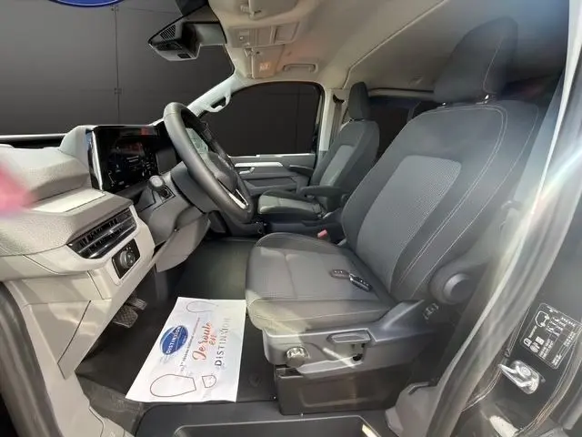 Vue intérieure côté conducteur du Volkswagen Transporter noir 2026, montrant les sièges avant et le tableau de bord moderne.