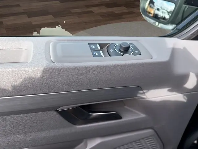 Détail de la porte côté conducteur du Volkswagen Transporter noir, avec commandes électriques des vitres et rétroviseurs.