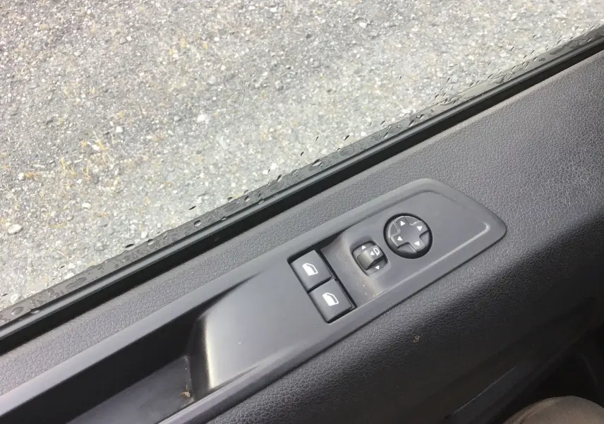 Gros plan sur les commandes de lève-vitres et réglage des rétroviseurs côté conducteur du Fiat Scudo Fourgon blanc 2024.