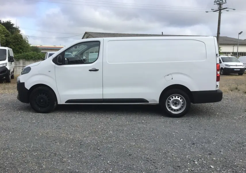 Vue de profil côté gauche d'un fourgon FIAT Scudo XL blanc 2024 avec garde au sol réhaussée et protections noires.